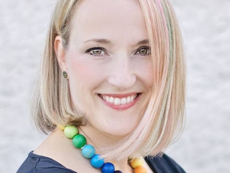 Portrait d'une femme souriante avec des cheveux blonds courts et un collier color&eacute;
