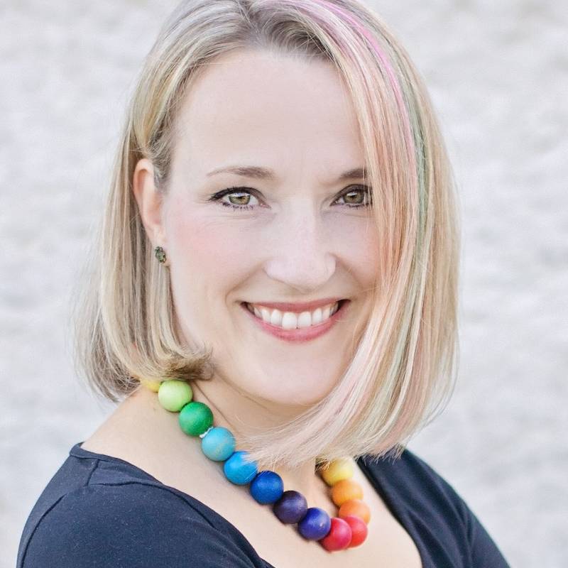 Portrait d'une femme souriante avec des cheveux blonds courts et un collier color&eacute;