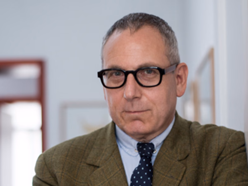 Homme portant des lunettes et un costume, regardant directement la cam&eacute;ra