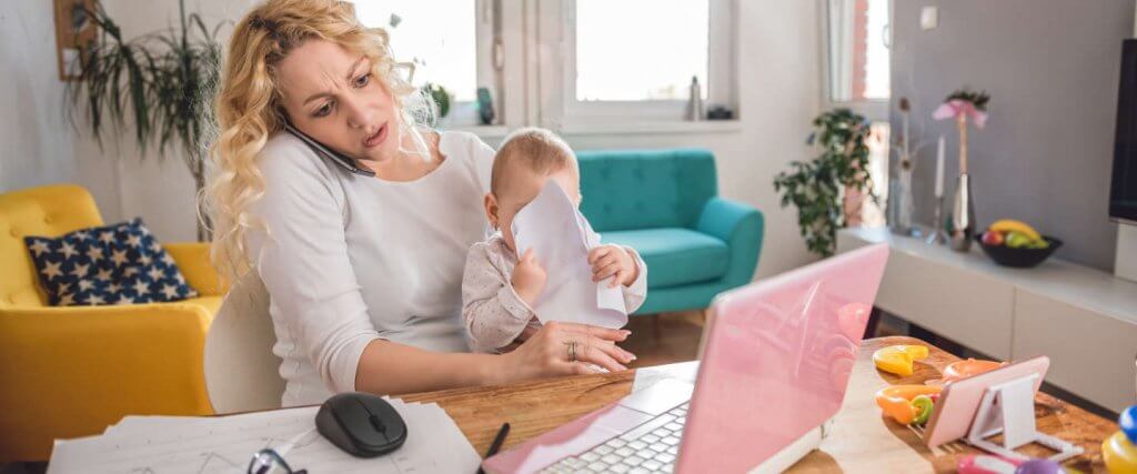 Gestresste Frau hält Baby, telefoniert und arbeitet am Laptop